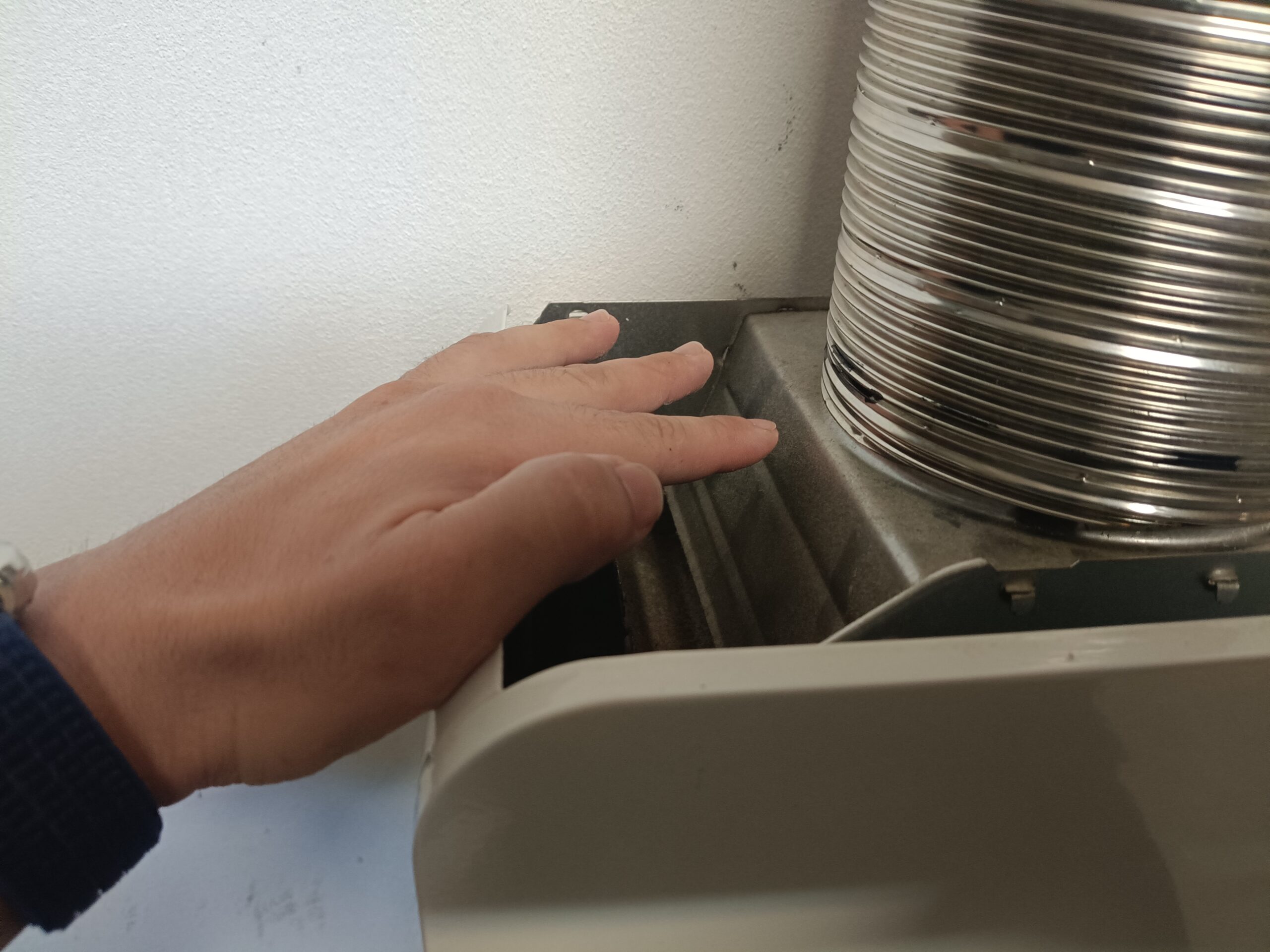 Dłoń trzymana nad górną częścią piecyka gazowego, bez dotykania obudowy i rury spalinowej